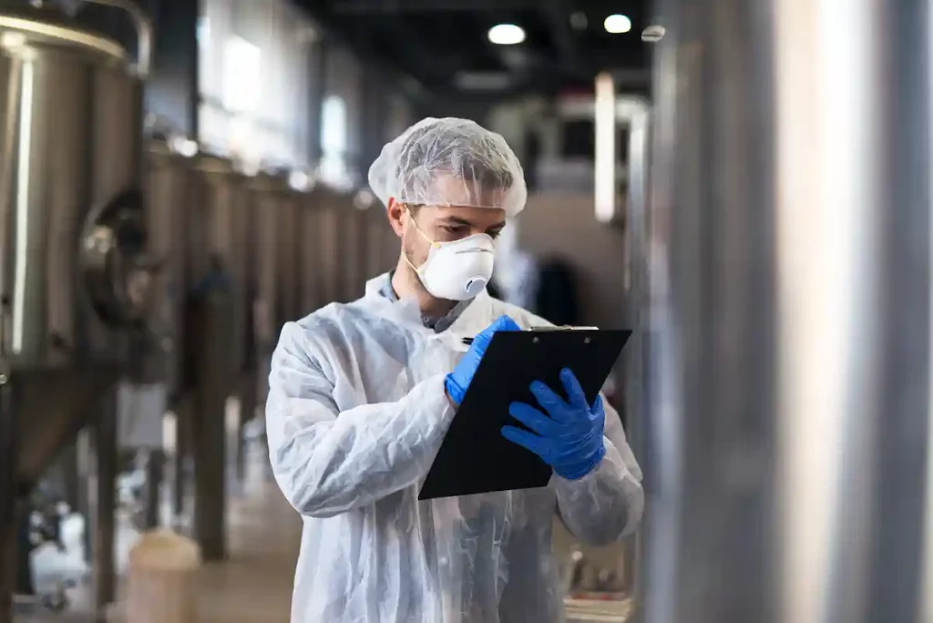 Responsable de calidad y consultor ambiental analizando residuos, envases y registros de cumplimiento en una empresa de la industria alimentaria